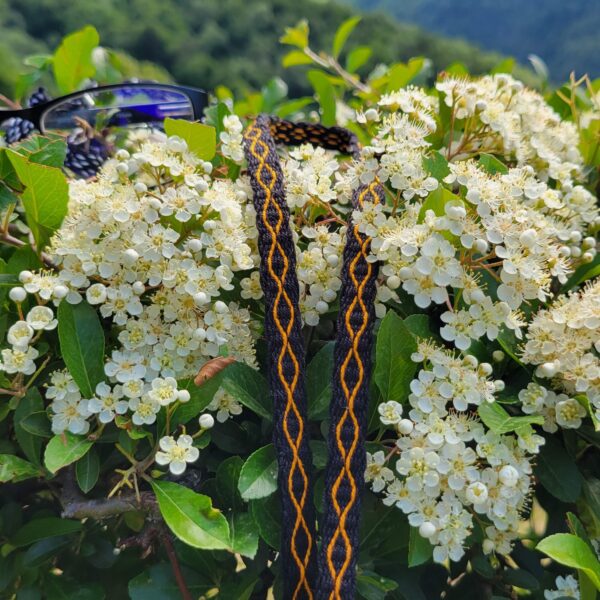 photo d'un cordon à lunettes tissé aux cartes noir avec un motif de torsades oranges